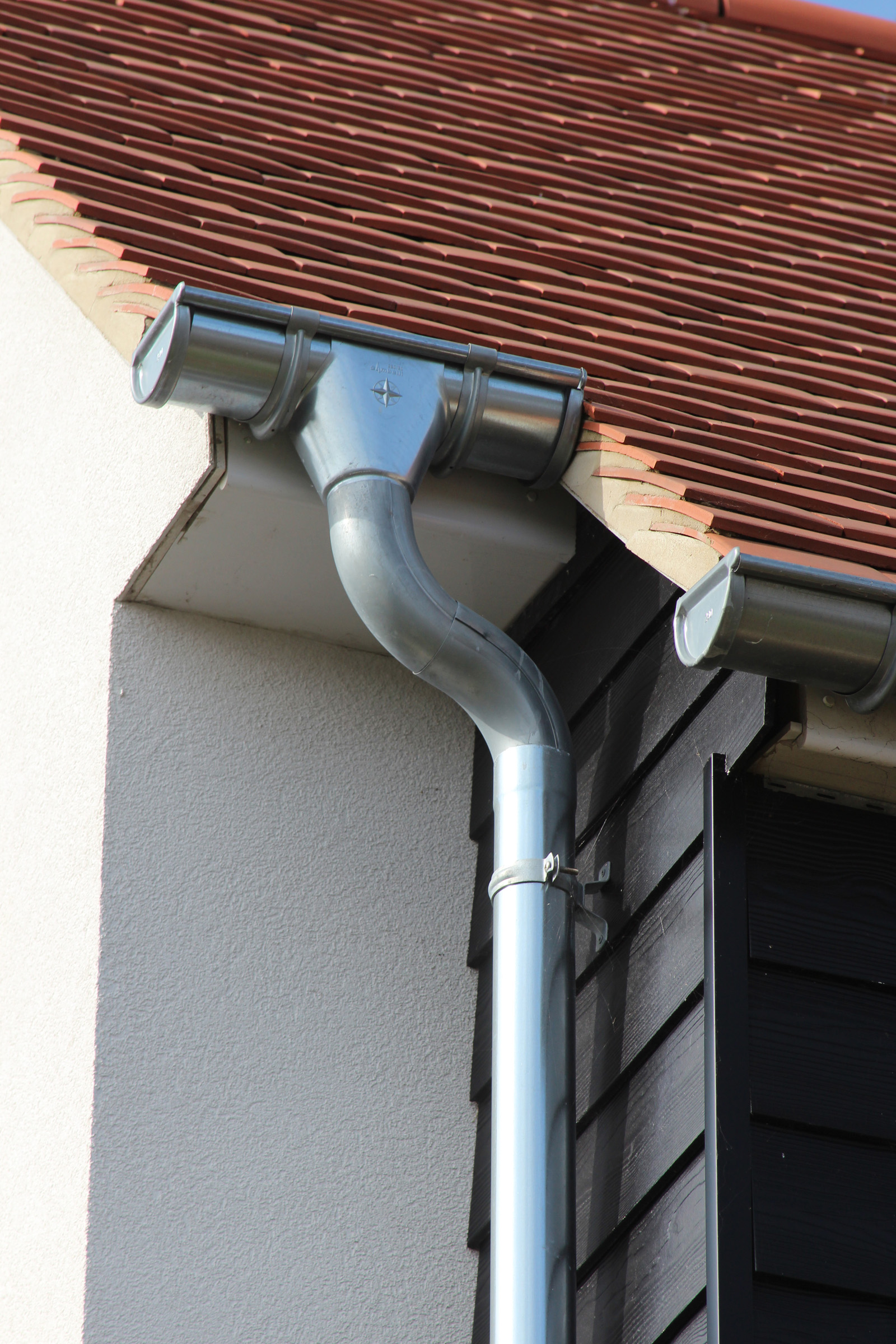 Gutter and downpipe join on a tiled roof
